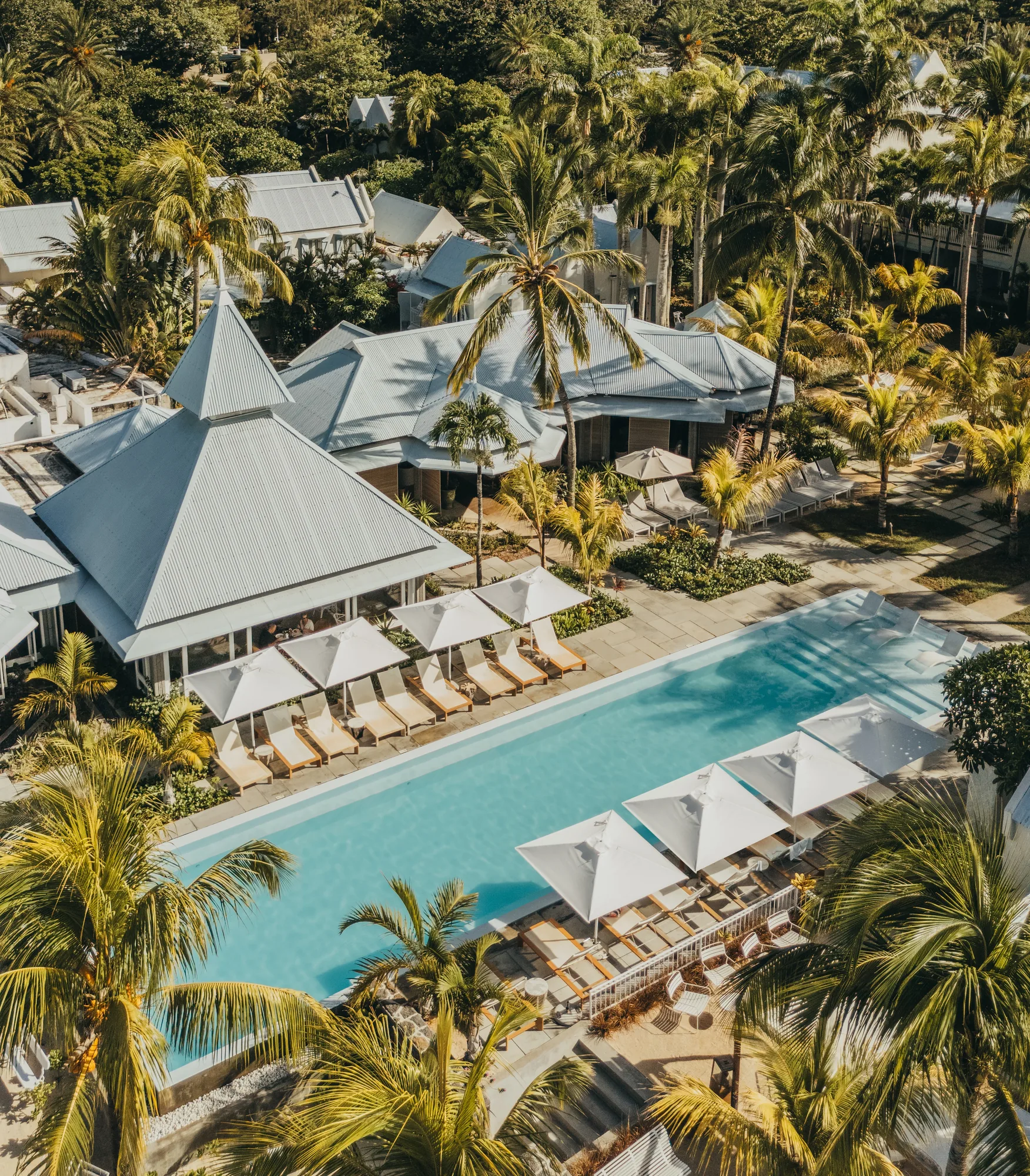 Aerial view of a long pool lined with parasols between the buildings