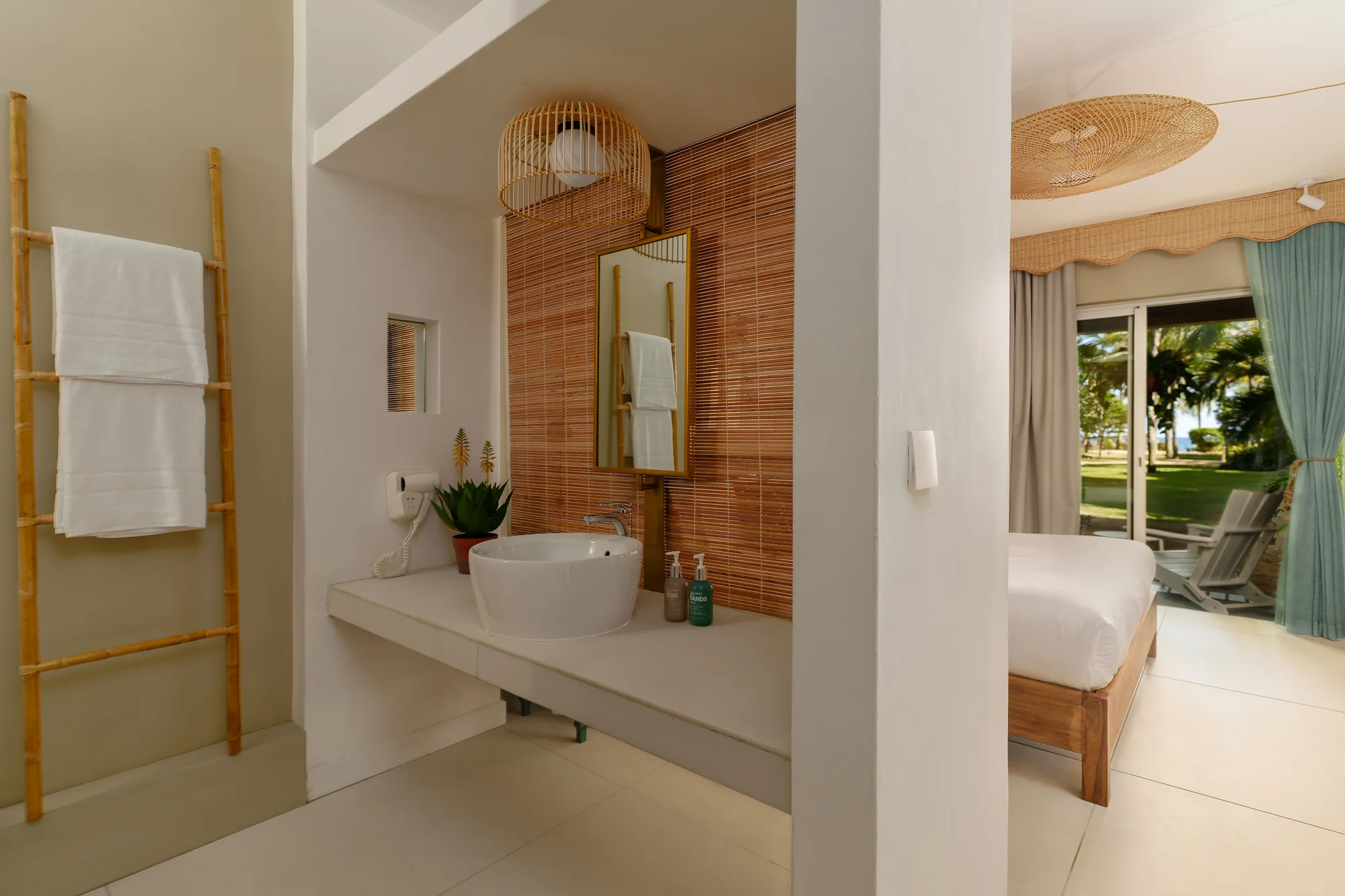 A bathroom basin behind a timber screen, beside the bedroom