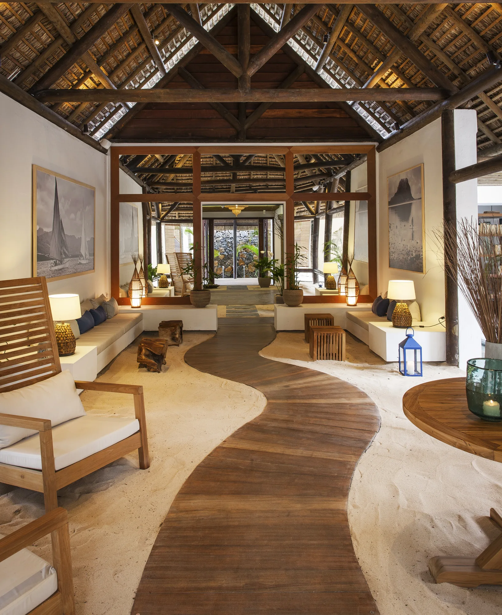 A timber walkway through a lounge under a high thatched roof