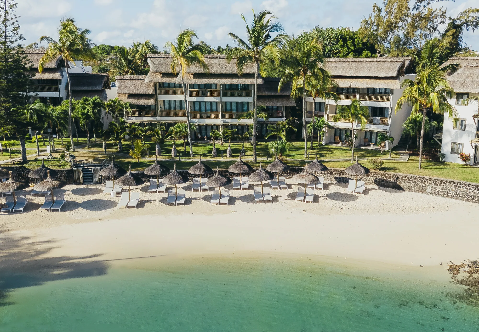 Aerial view of Veranda Paul & Virginie, its thatched buildings behind a beach of thatched parasols