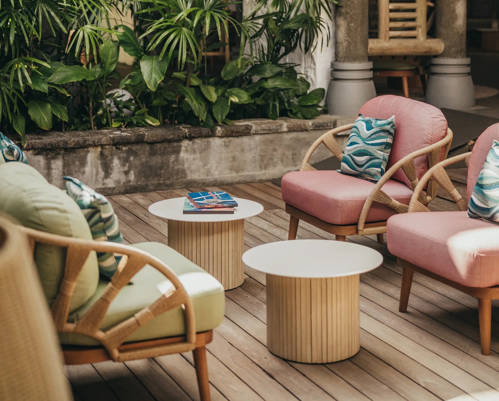 A terrace with pink and green armchairs among tropical plants