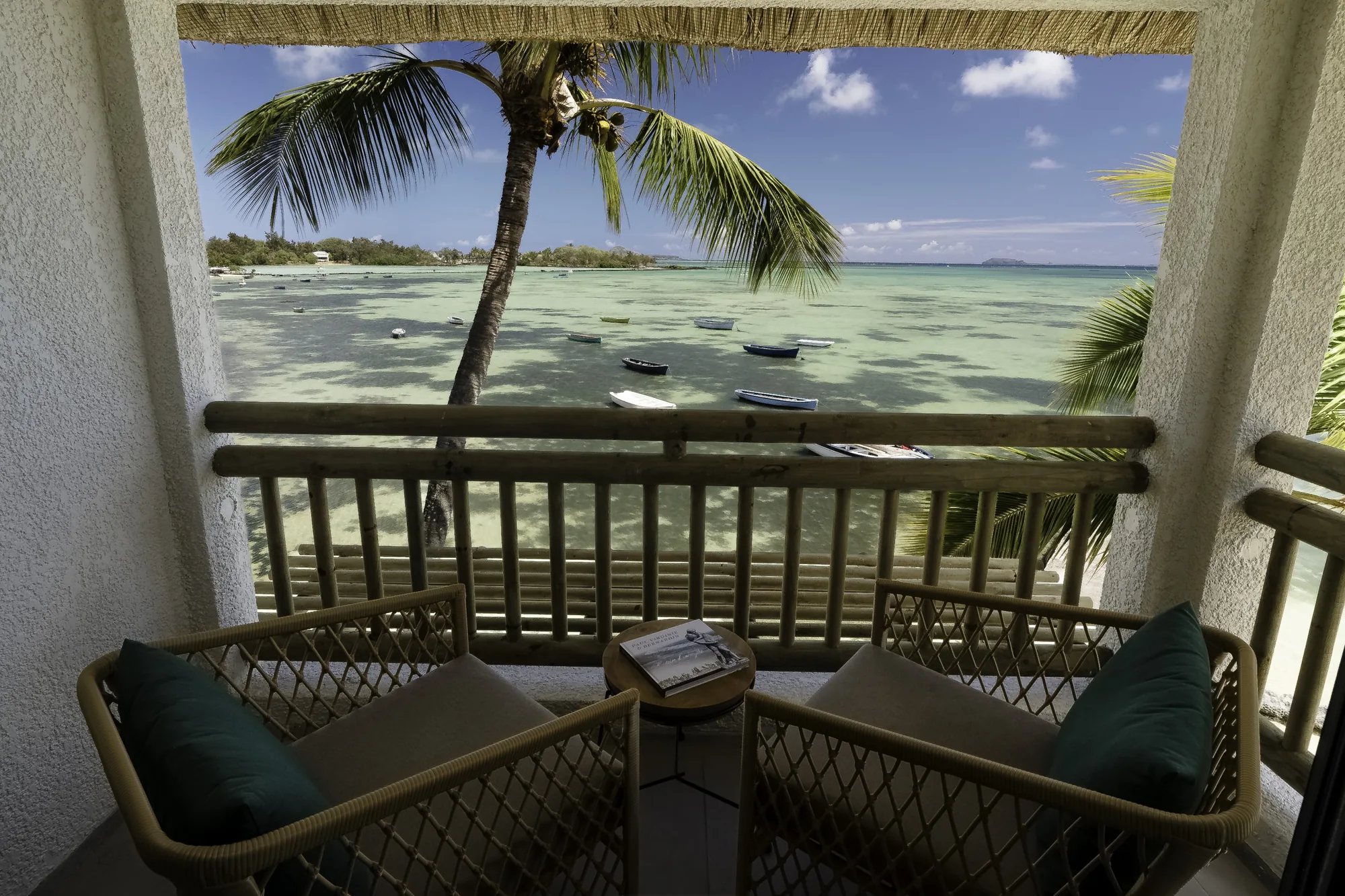 Two cushioned armchairs on a balcony looking out over the lagoon