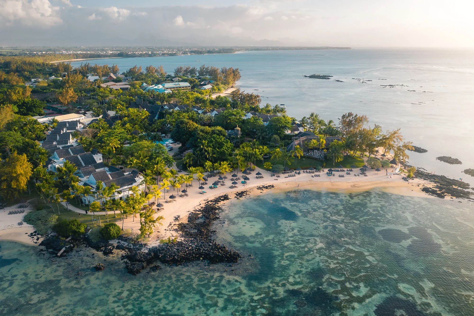 Aerial view of Canonnier Beachcomber on its headland, the beach curving around a rocky lagoon