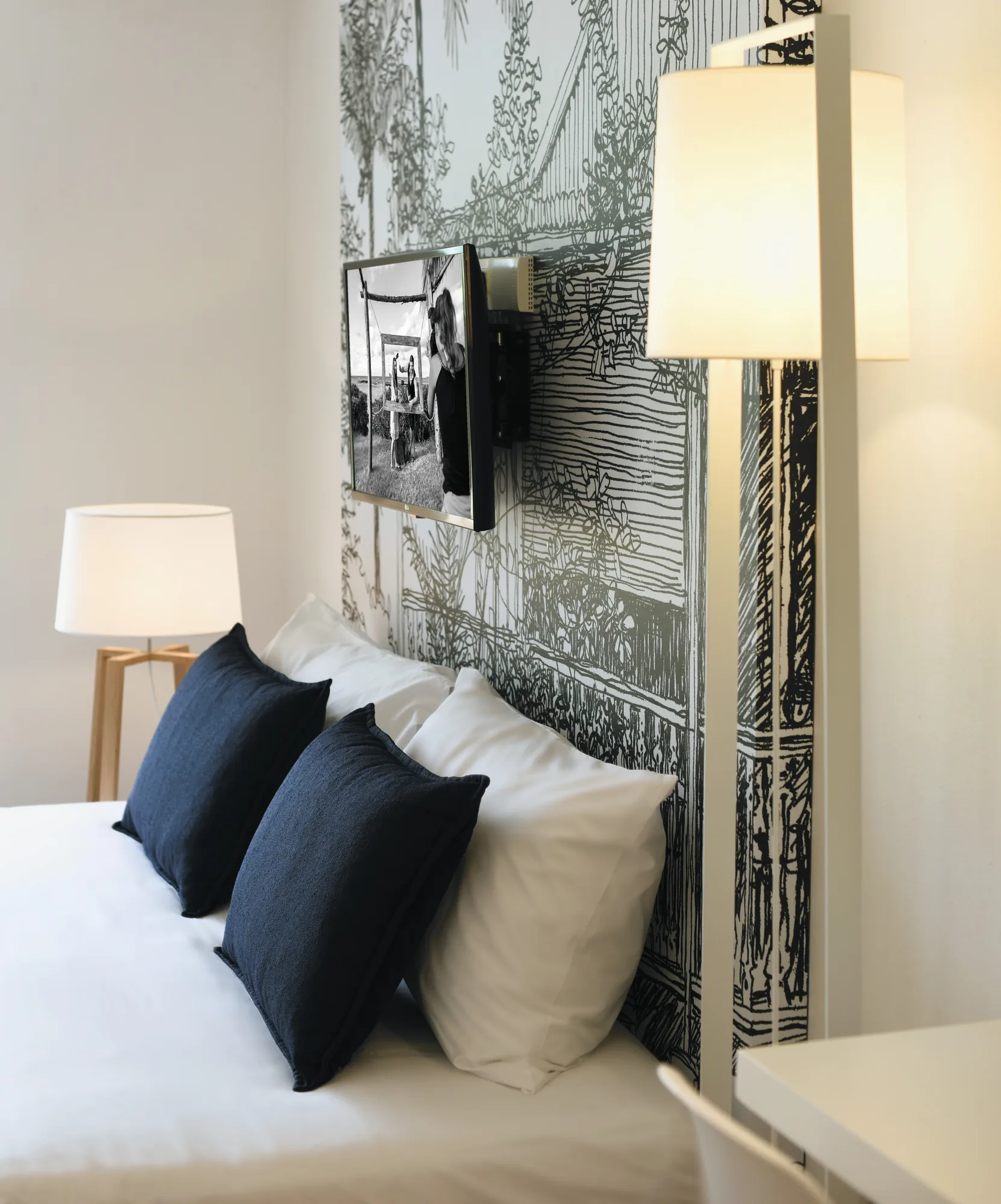 A bed with navy cushions against a patterned wall