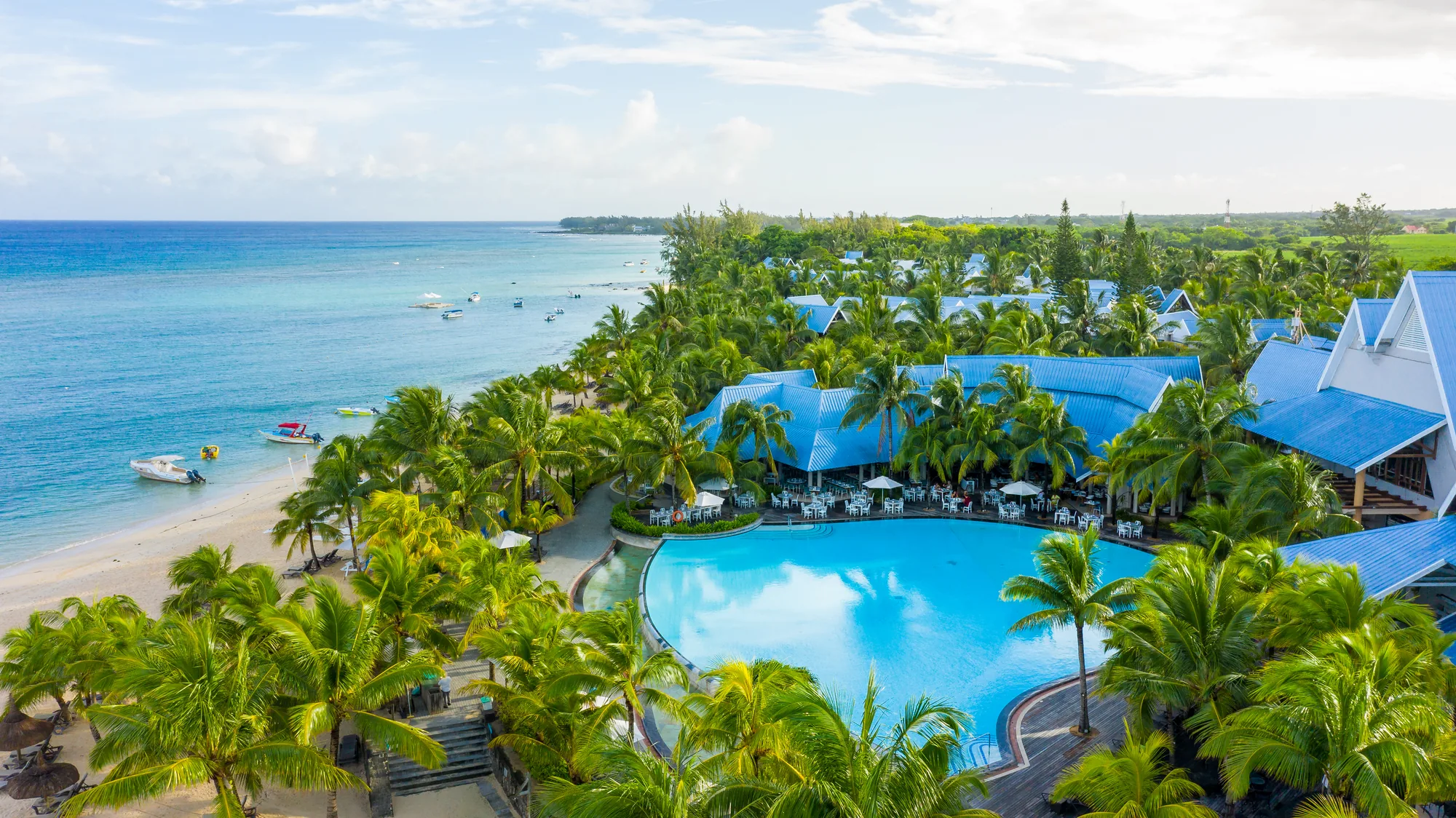 Aerial view of Victoria Beachcomber, its blue roofs and large pool beside the beach