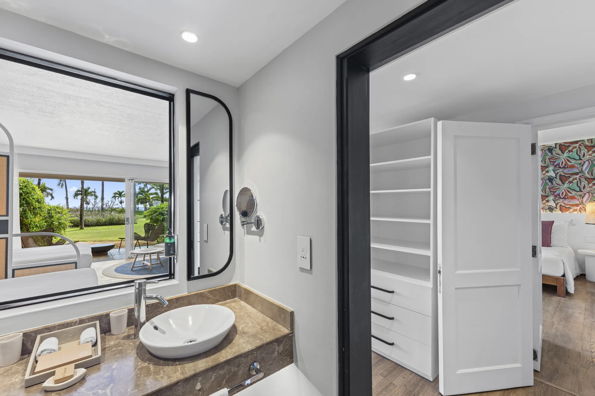 A bathroom with a basin and an internal window onto the bedroom