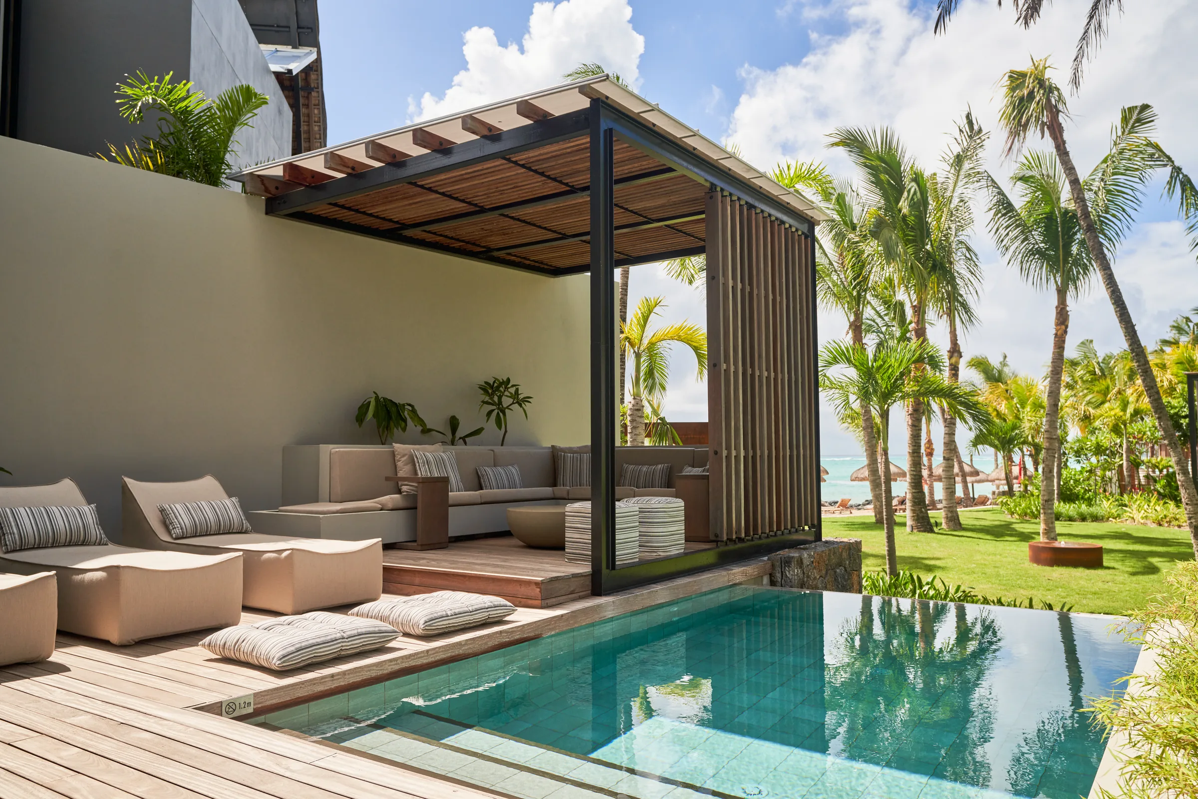 A private terrace with outdoor sofas under a pergola beside a plunge pool