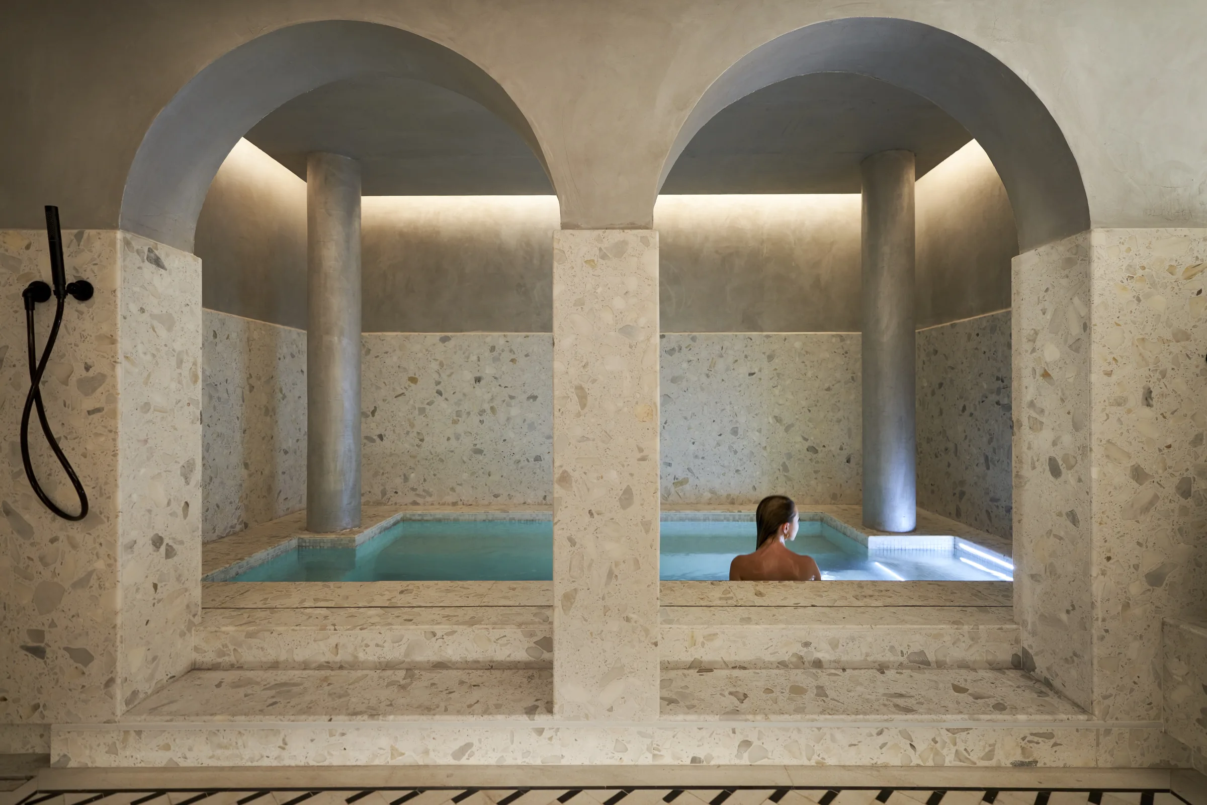 A guest in a pool beneath stone arches in the spa