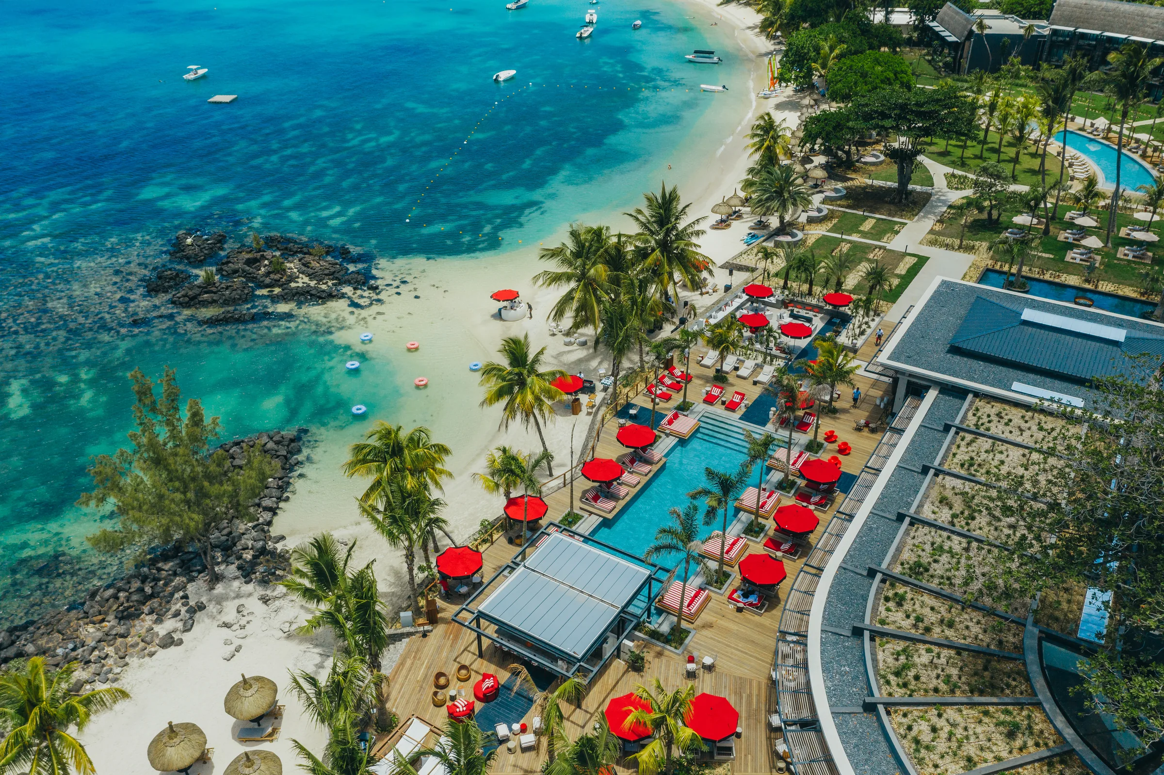 Aerial view of the beach, red parasols and pools beside the lagoon