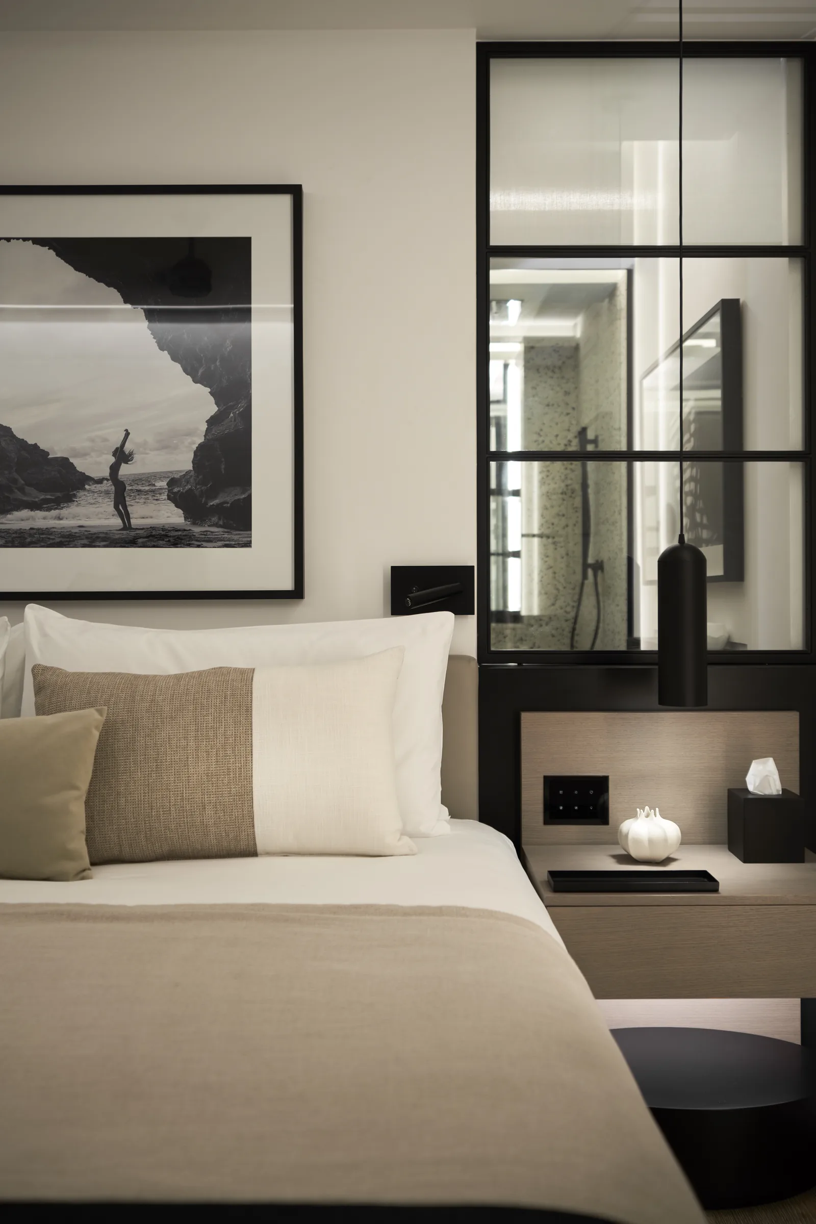 A bedroom with a black and white photograph above the bed