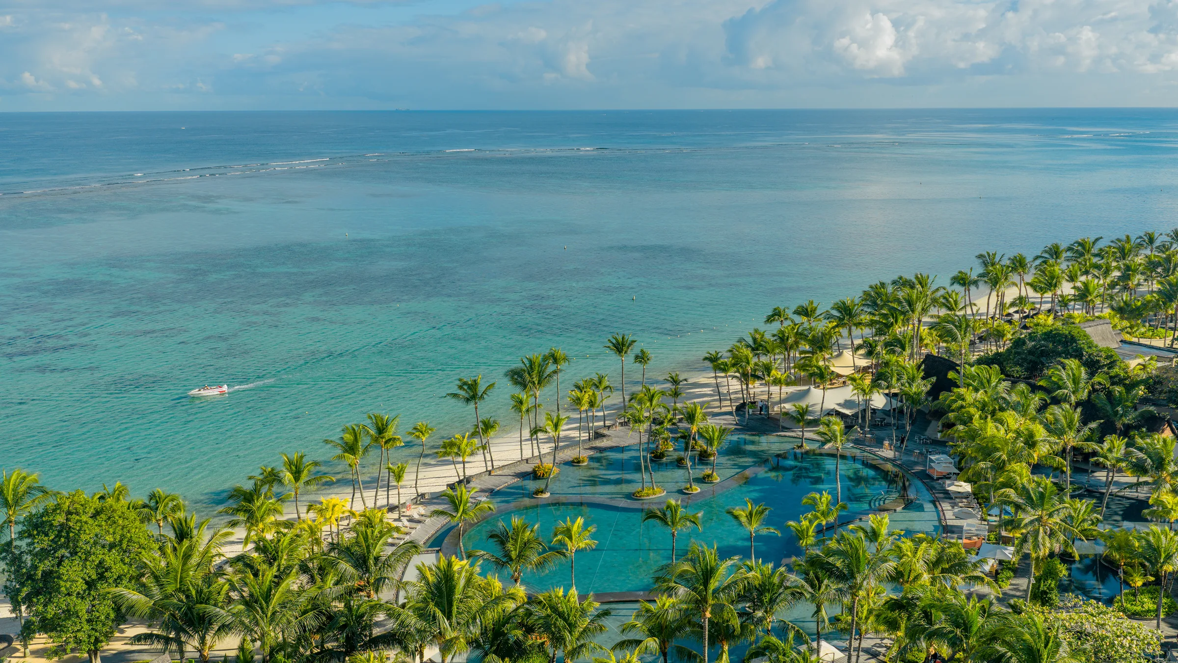 Aerial view of Trou aux Biches Beachcomber, its pools among palm trees along a long beach and lagoon