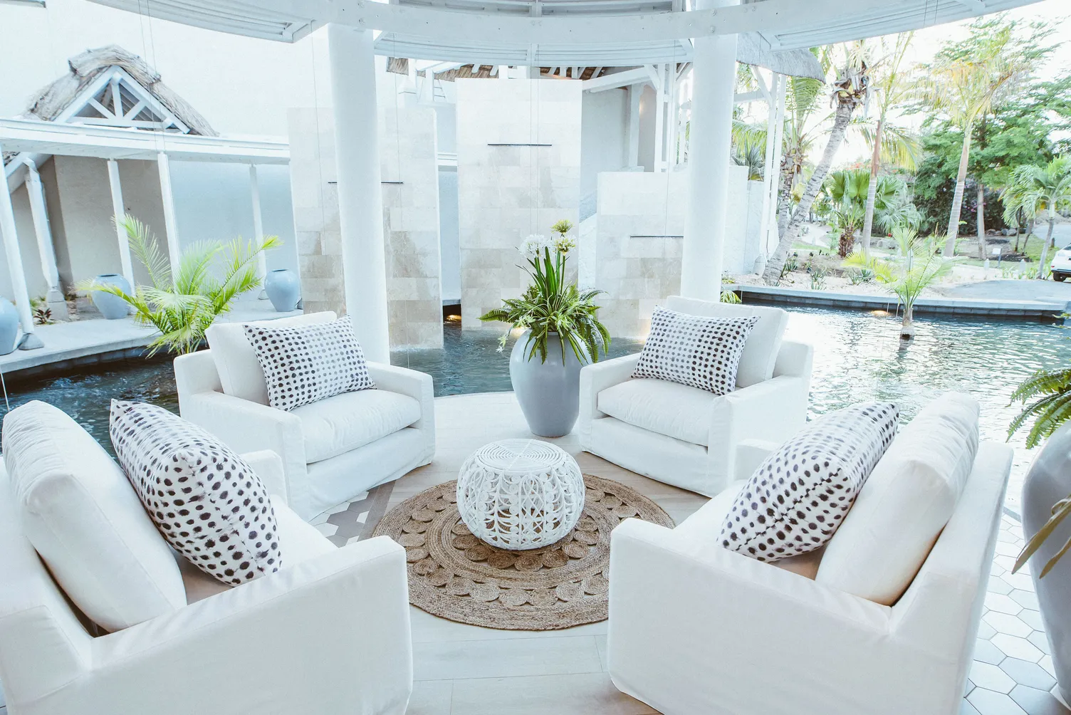 White armchairs around a low table in a courtyard lounge with a water feature