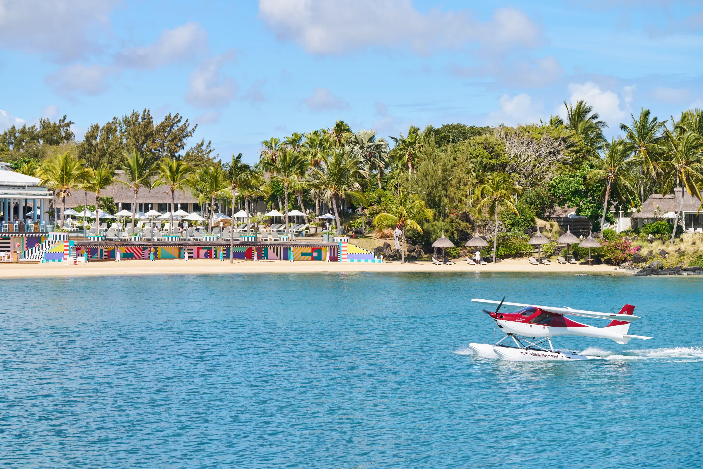A seaplane on the lagoon in front of the resort's beach and colourful beach restaurant