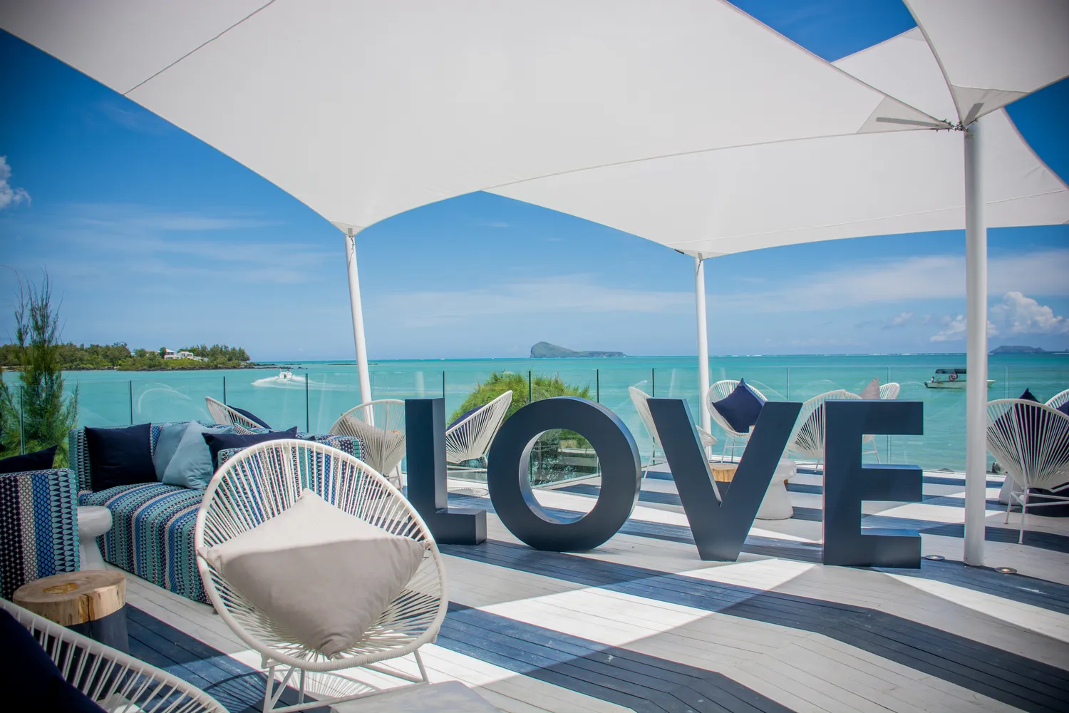 Large LOVE letters on a deck with chairs and shade sails facing the sea