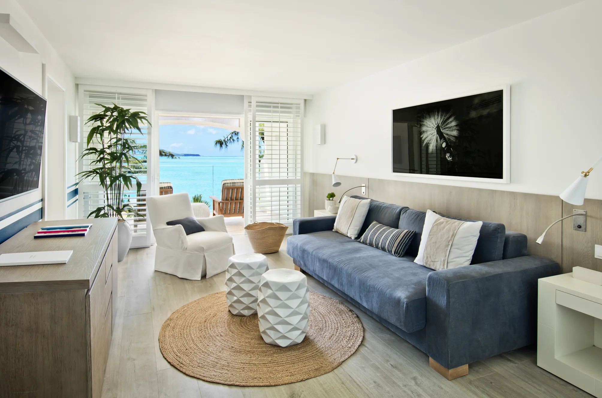 A sitting room with a blue sofa and shutters open to the sea