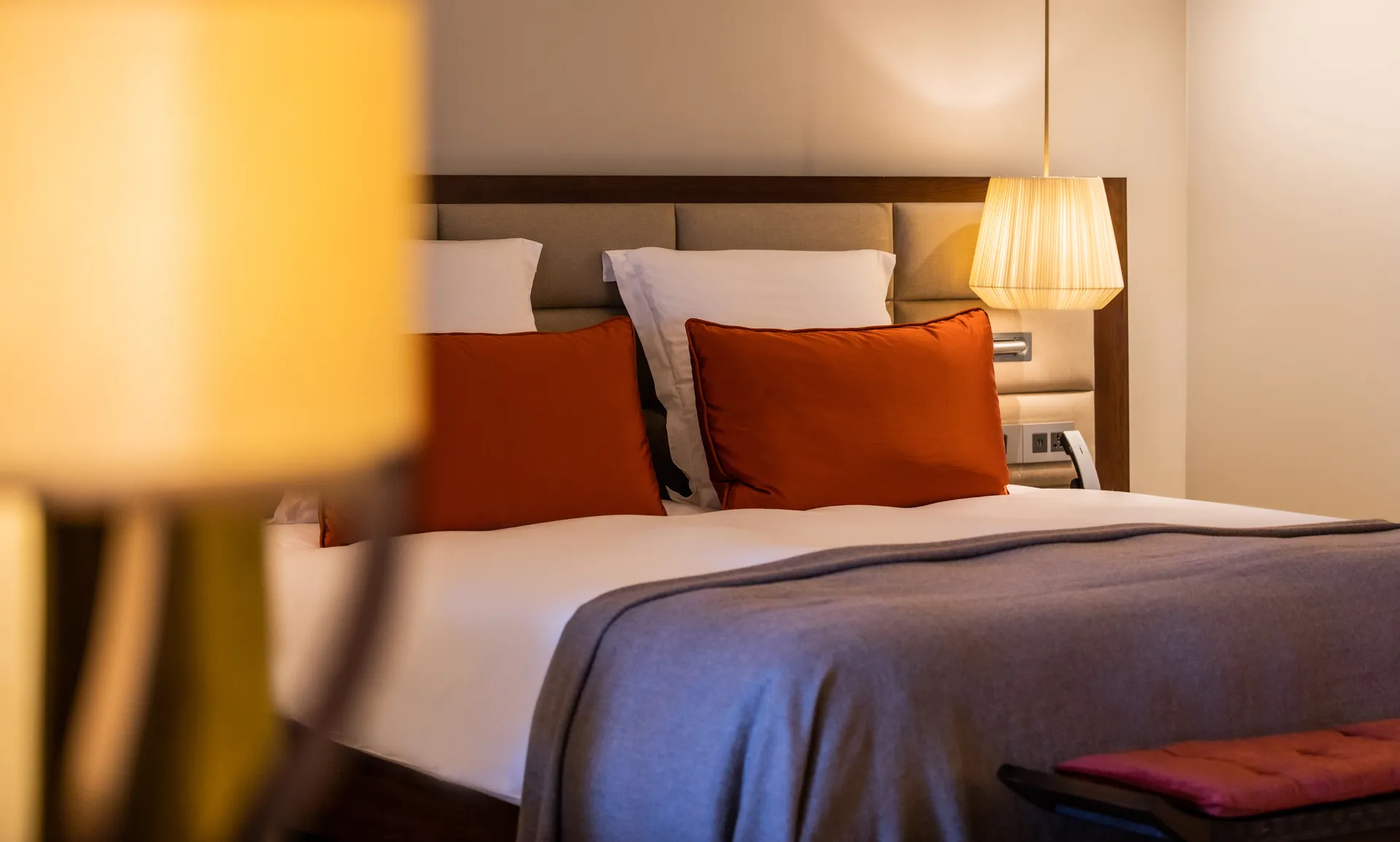 A bed with orange cushions in soft lamplight
