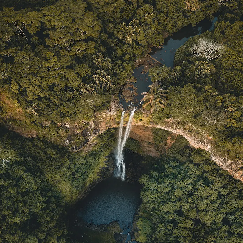 Aerial view of a waterfall dropping into a forest pool