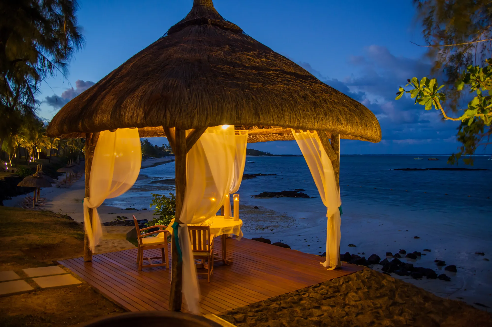 Boats floating near lush green hills and thatched-roof resort in Mauritius—Island Lilly’s curated leisure and exploration experiences