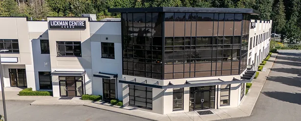 Modern commercial building labeled "Lickman Centre" with white walls, large dark-tinted glass windows, and a corner entrance.