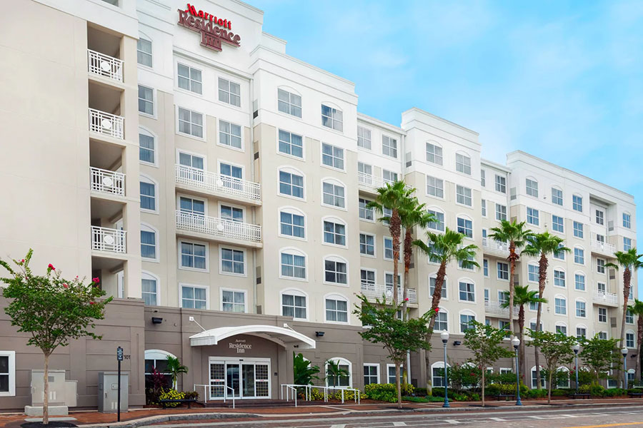 Front view of a multi-story Marriott Residence Inn hotel with palm trees and a clear blue sky.