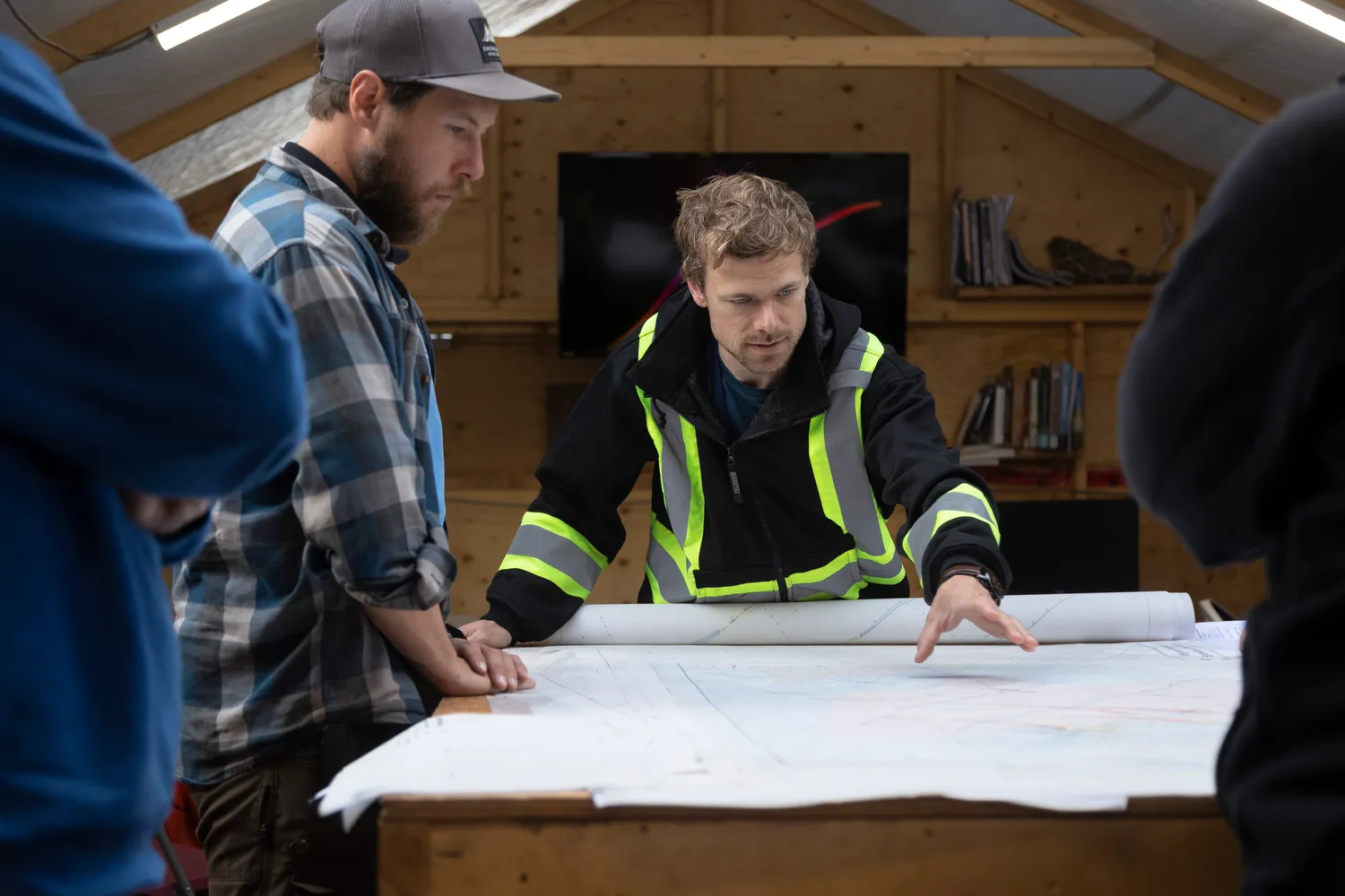 4 people discussing their plan with a map laid out on a table