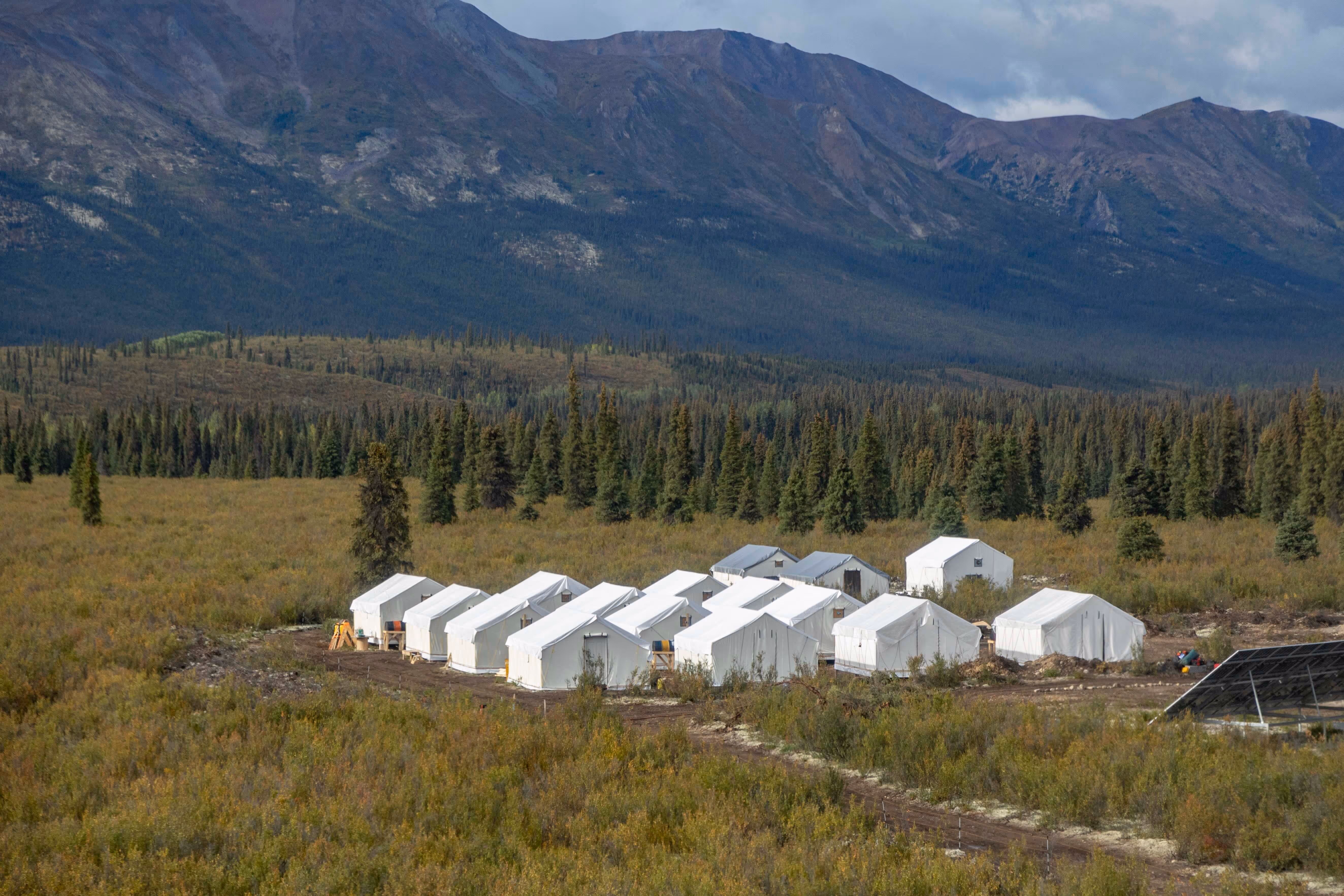 A group of white tents are set up in a field.