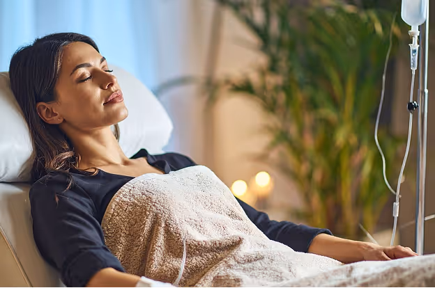 Woman receiving IV infusion at ThrIVwell, covered with a soft blanket in a calming wellness environment.