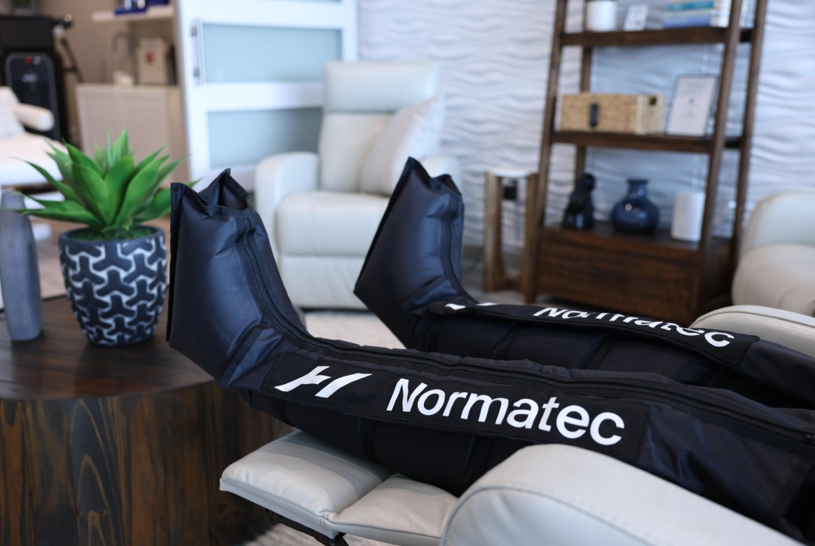 Patient undergoing Normatec compression therapy at ThrIVwell, seated comfortably in a modern recovery room.