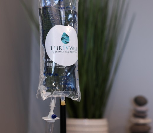 Woman receiving IV infusion at ThrIVwell, covered with a soft blanket in a calming wellness environment.