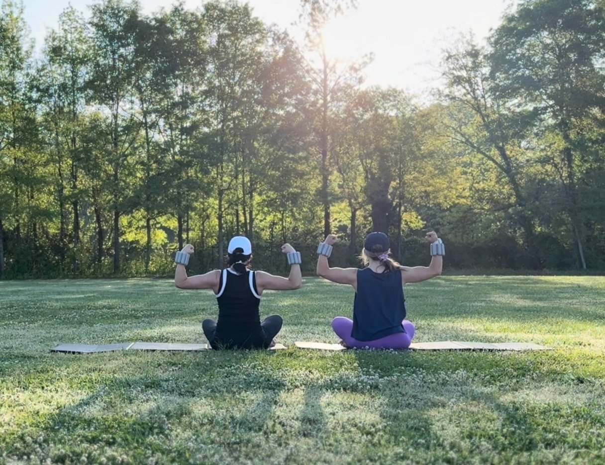 Two women sitting outside working out