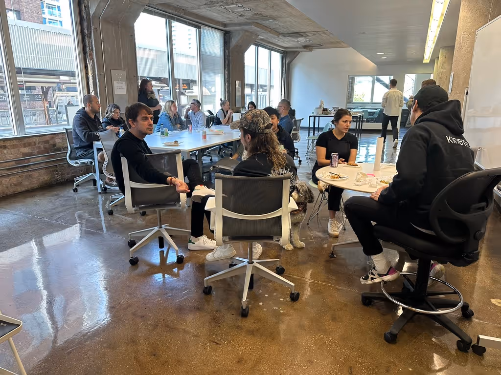 Group of people seated in an open office space engaged in a casual meeting and conversation.