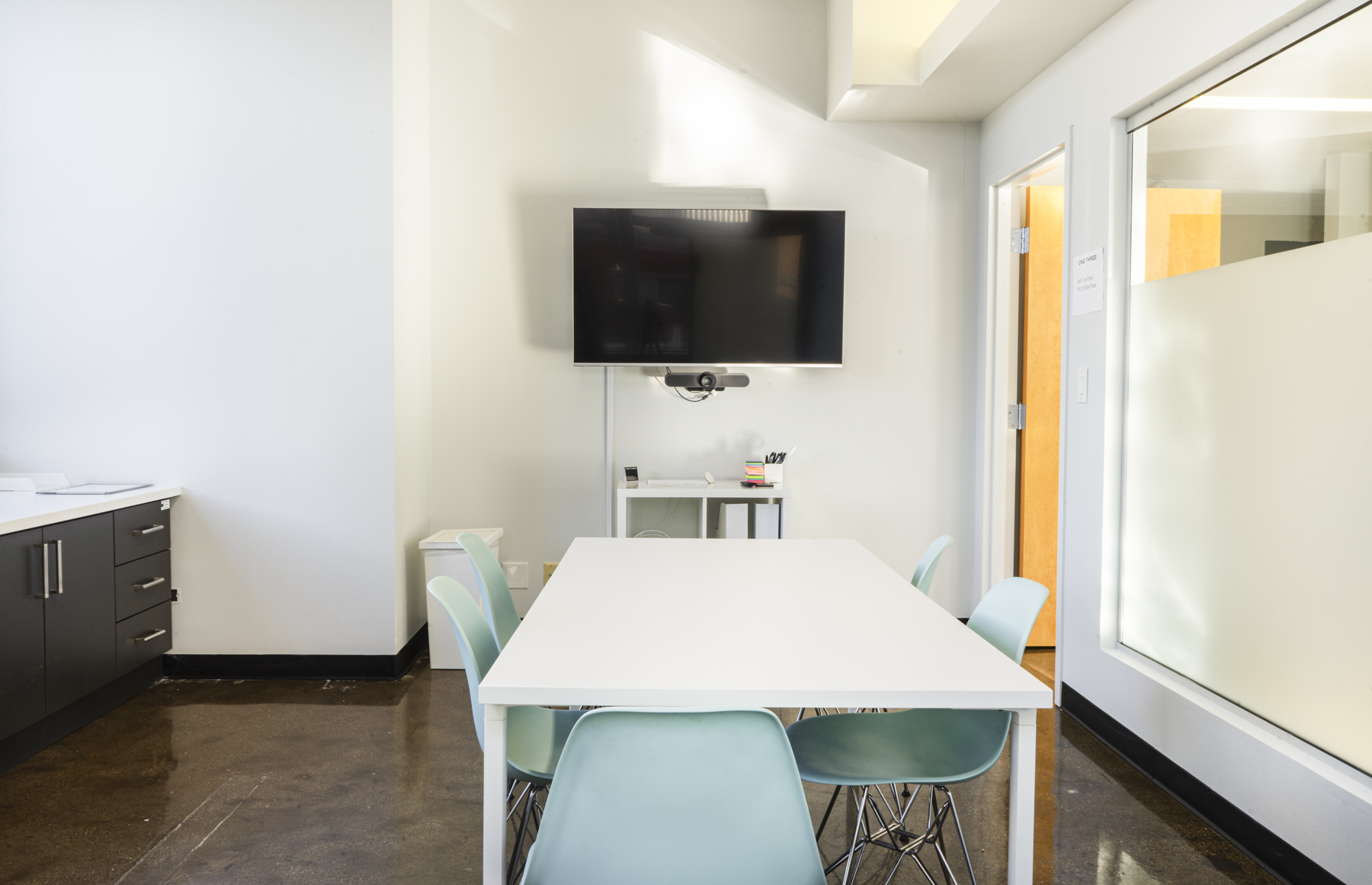 Detail of the 3:7 Conference Room with light blue chairs around the meeting table