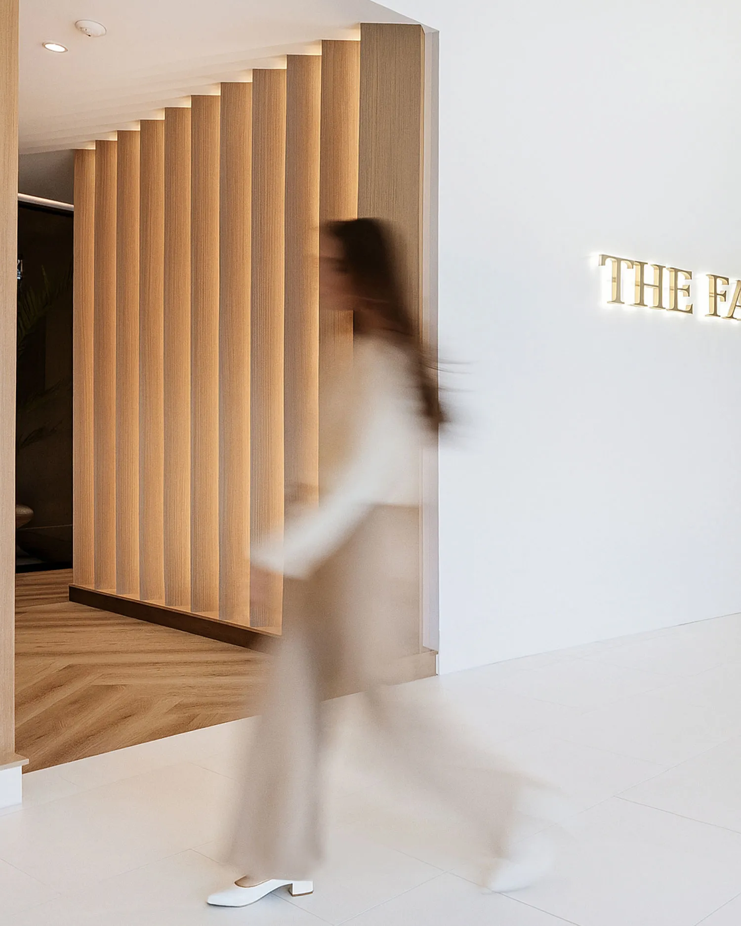 A blurry photo of a woman walking past a sign.