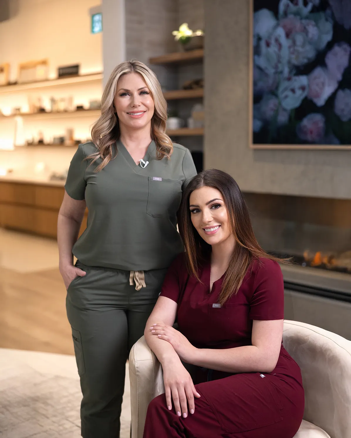 Two women in scrubs sitting on a couch.