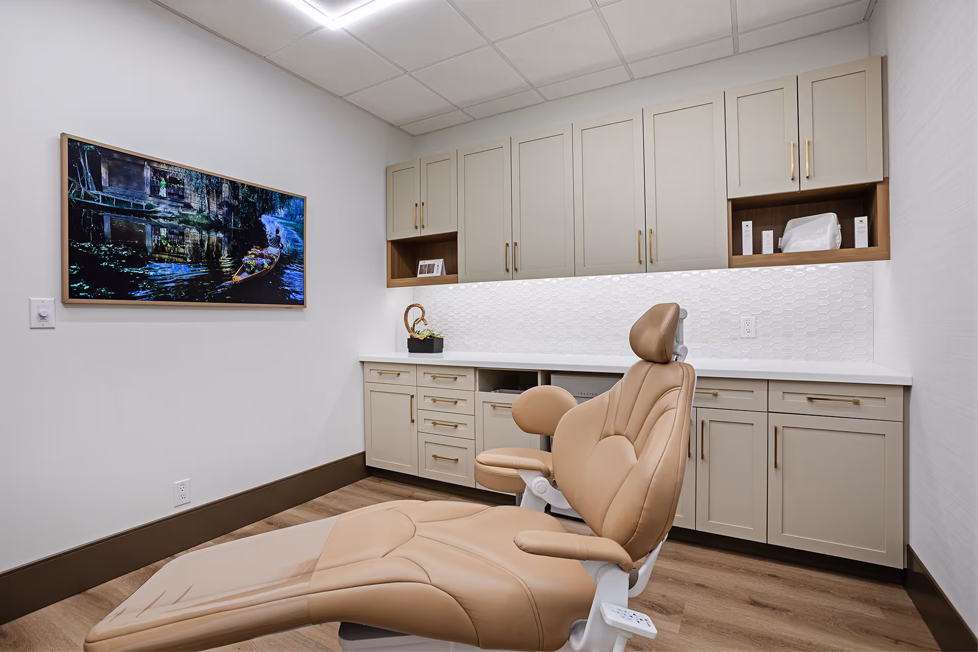 A room with a clinic chair, cupboards and wall art