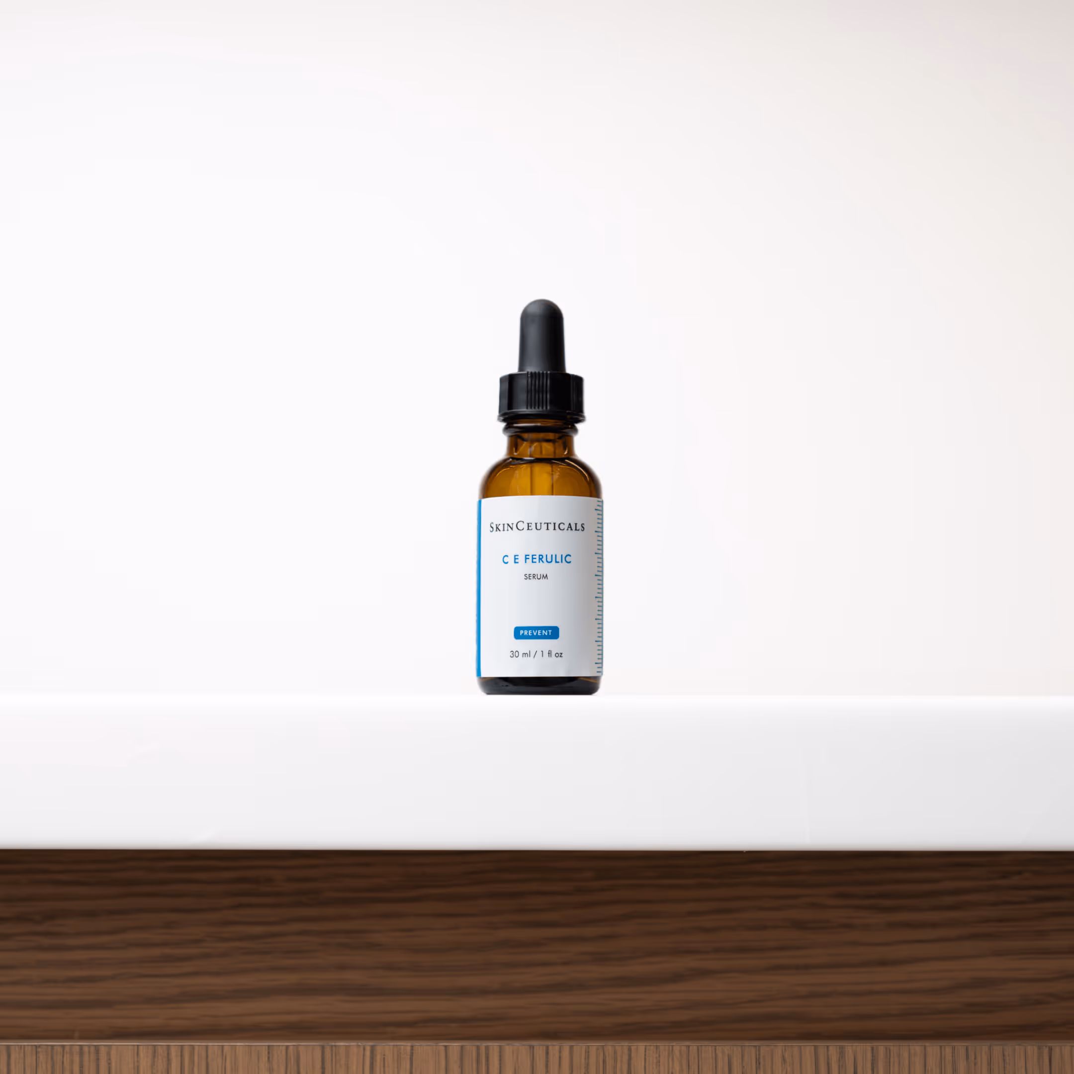 SkinCeuticals C E Ferulic serum bottle with dropper on a white surface and wood background.