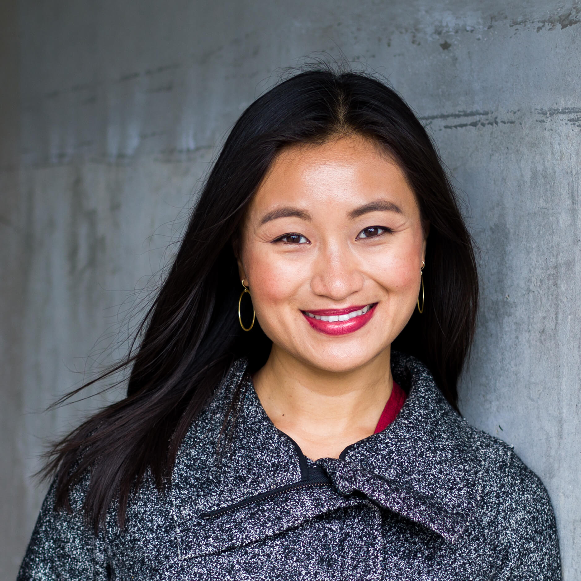Headshot of Chenxing Han wearing a dark gray jacket against a gray wall. 