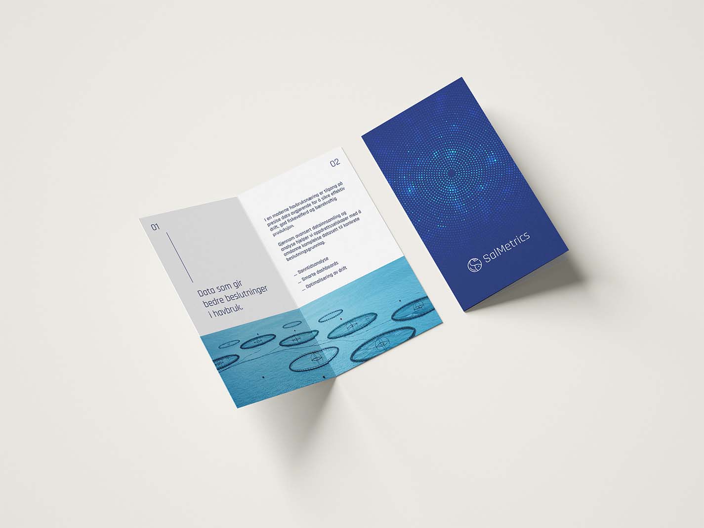 Åpen brochure med blått sjøbrukstema ved siden av lukket blå booklet.