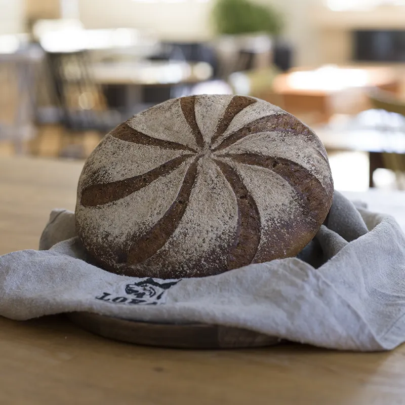 Runt mjukt bröd med swirlmönster pudrat med mjöl på linneservett på träbord.