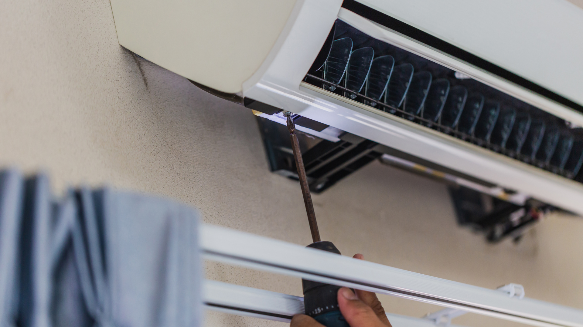 Technician repairing an air conditioning unit with a screwdriver, illustrating AC maintenance and repair services.