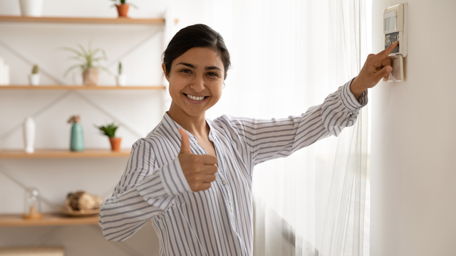happy woman clicking the thermostat with thumbs up