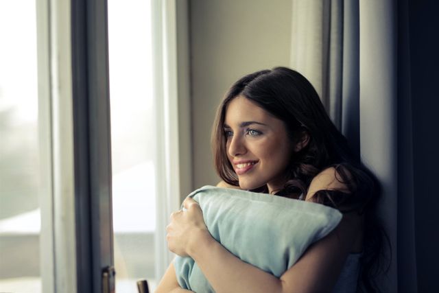 Picture of a woman sitting next to a window.