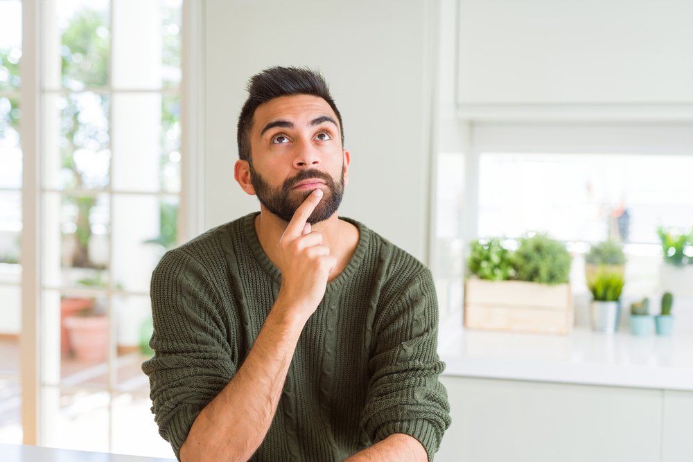 Man contemplating in a modern kitchen, considering options for dual fuel heating systems.