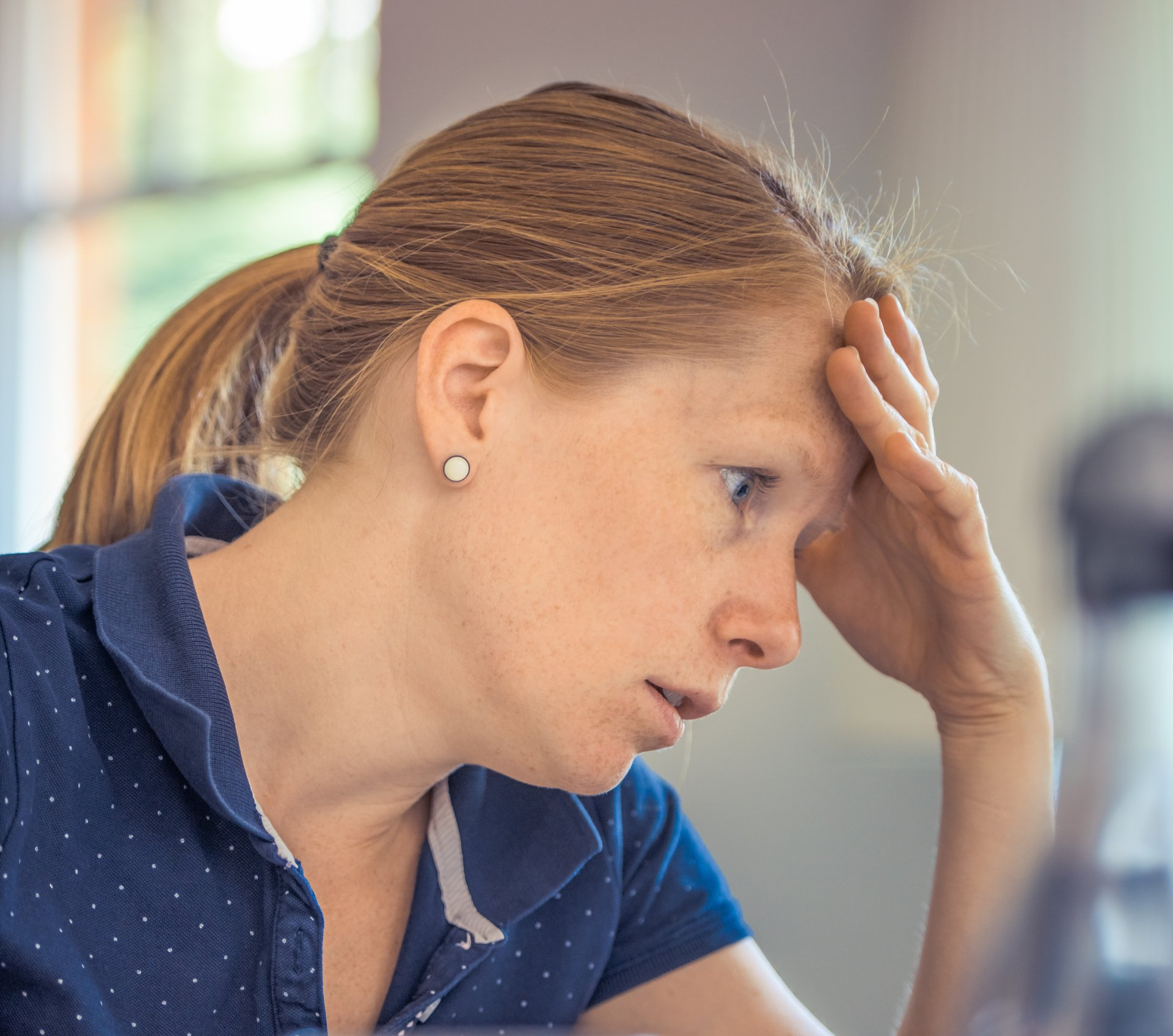 Woman with a worried expression, hand on forehead, indicating stress or concern, relevant to troubleshooting furnace issues.