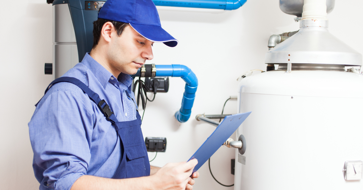 Technician inspecting heat pump water heater, surrounded by plumbing and HVAC equipment, emphasizing installation and maintenance services.