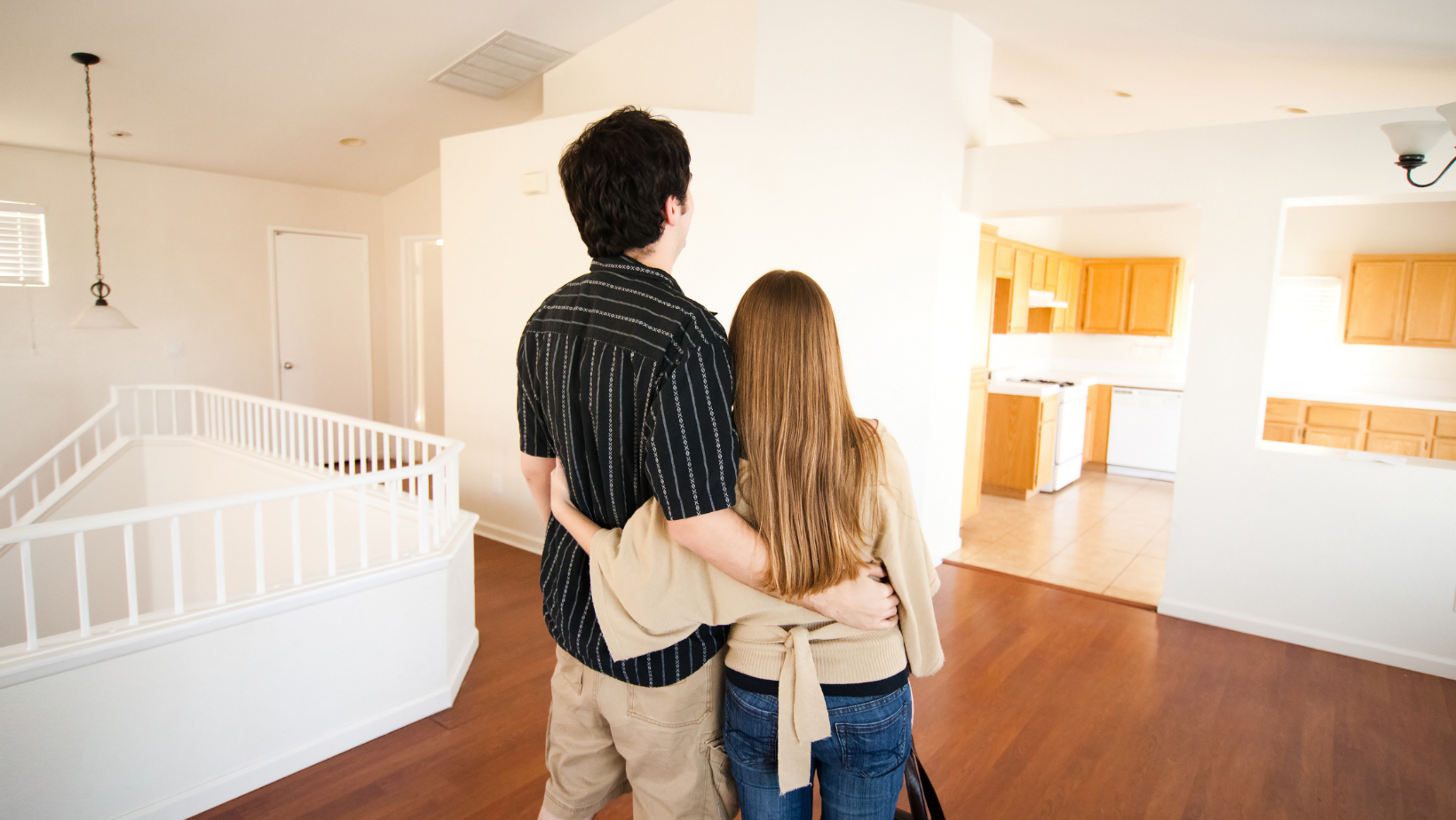 Couple standing in a spacious, newly renovated home, contemplating HVAC installation for summer comfort.