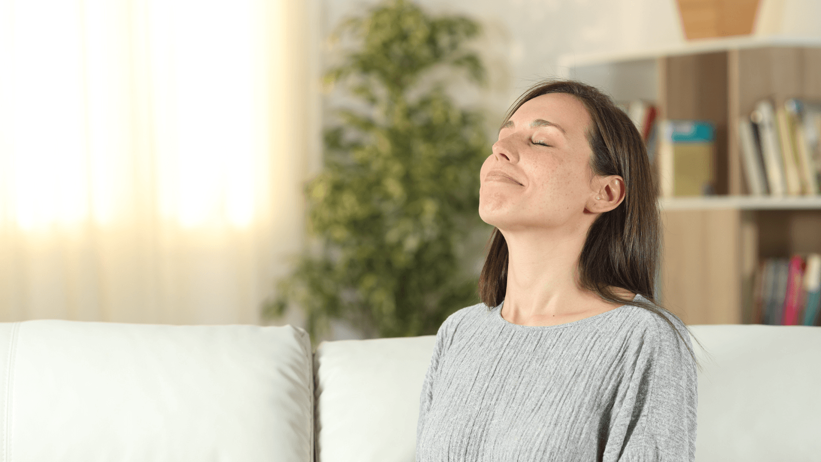 Woman enjoying clean air indoors, demonstrating the benefits of air purification for improved indoor air quality.