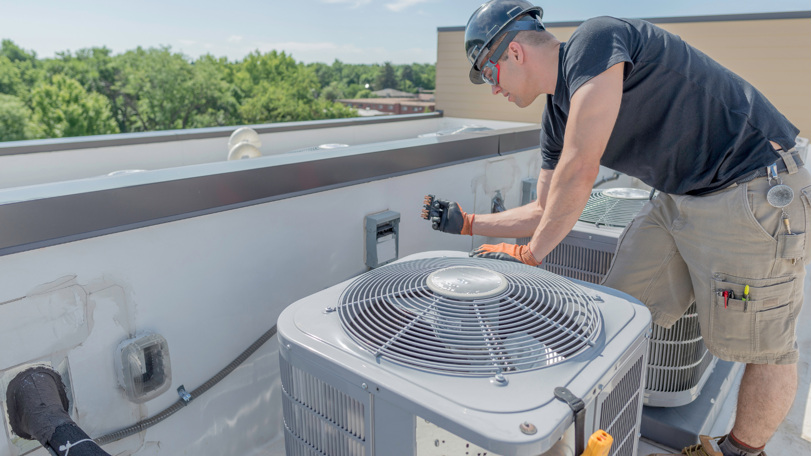 HVAC technician performing maintenance on rooftop air conditioning units, ensuring optimal performance and longevity during fluctuating weather conditions.