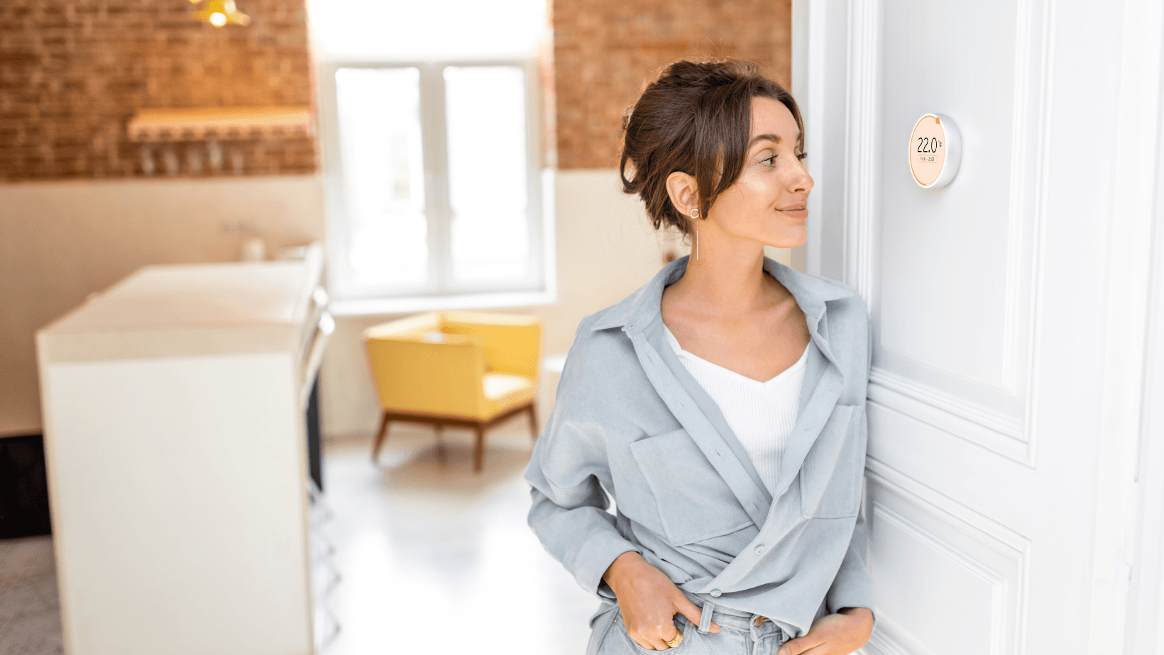 Woman adjusting a modern thermostat displaying 22°C in a stylish home setting, illustrating the importance of thermostats for HVAC energy efficiency.