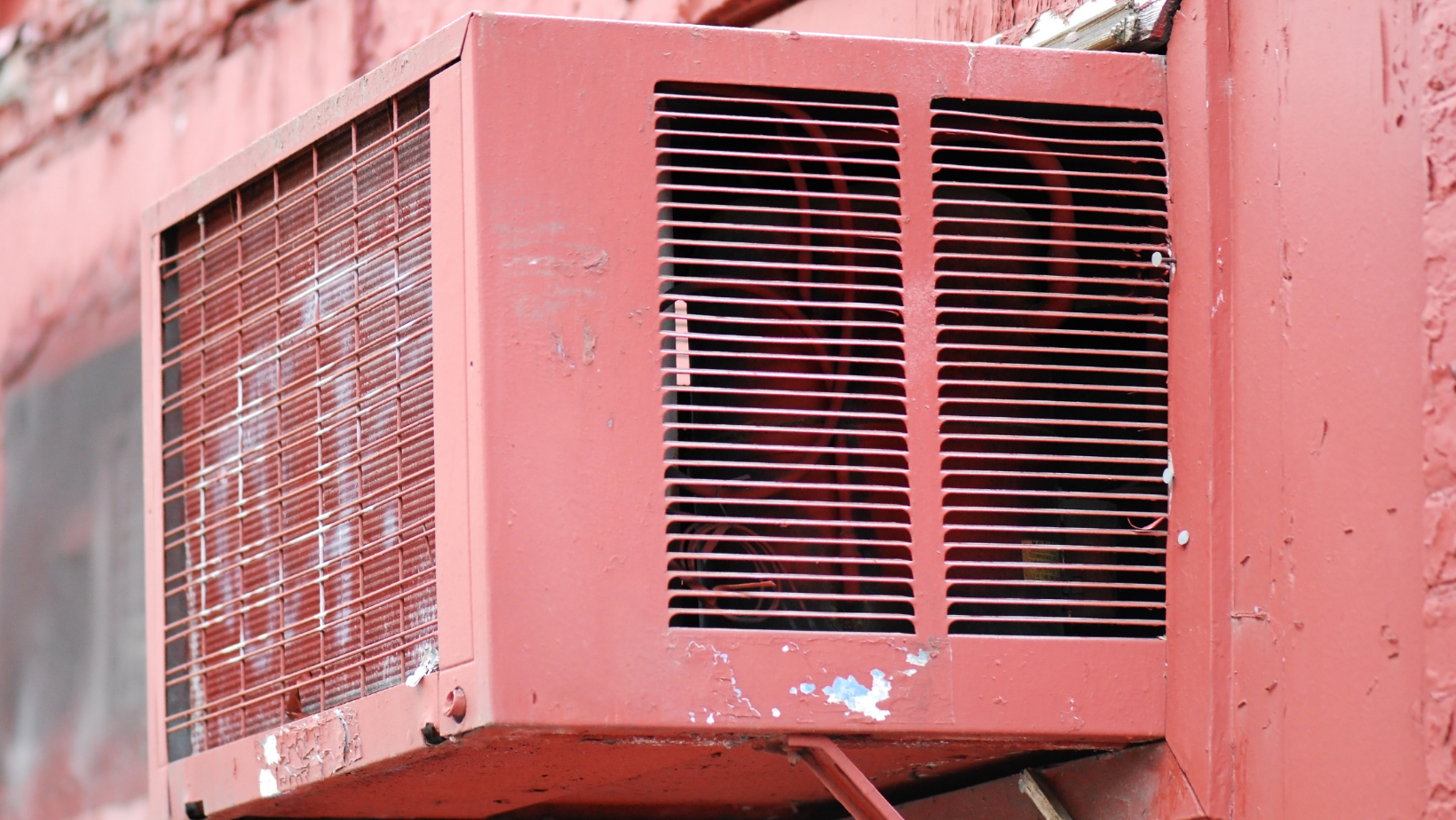 Old air conditioning unit mounted on wall, showing signs of wear and tear, relevant to HVAC maintenance and upgrade discussions.